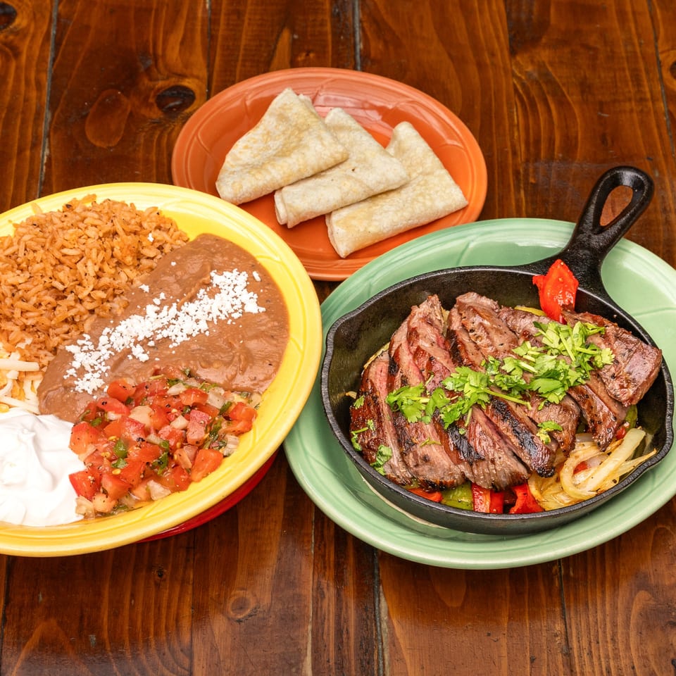 Que Pasa Cantina's sizzling steak fajitas with rice, beans, pico de gallo, and tortillas.