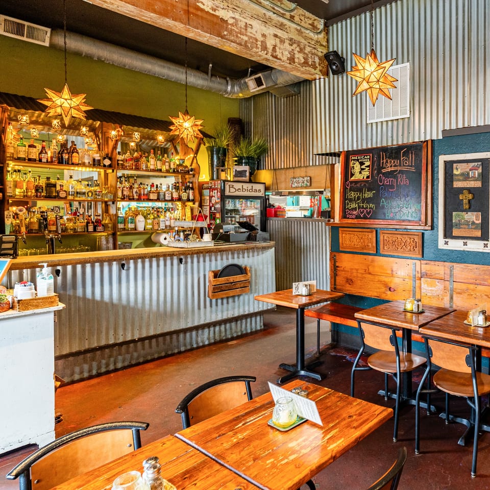 Que Pasa Cantina's interior features a corrugated metal bar, wooden tables, and star-shaped lights.